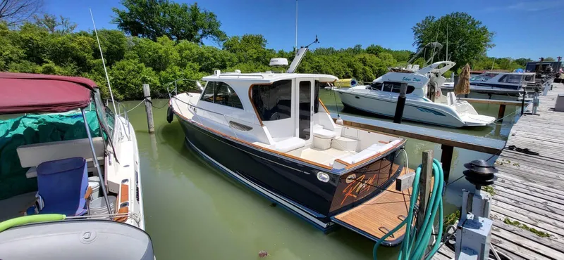  Yacht Photos Pics 2022 Legacy 36 boat docked at marina, surrounded by lush greenery and clear blue sky.