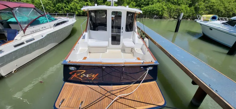  Yacht Photos Pics 2022 Legacy 36 boat docked in a marina, surrounded by lush greenery.