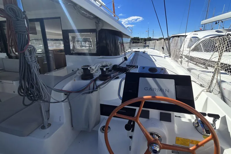  Yacht Photos Pics 2025 Excess 14 yacht cockpit with Garmin navigation, ropes, and steering wheel under clear blue sky.