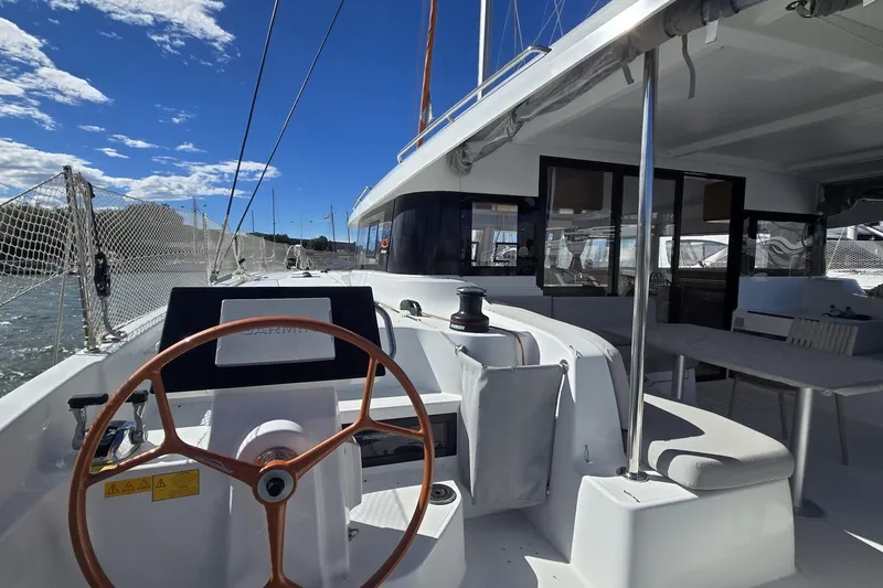  Yacht Photos Pics 2025 Excess 14 yacht cockpit with steering wheel, spacious deck, and clear blue sky.