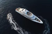 Aerial view of 2022 Amels Custom yacht cruising with a small boat nearby.