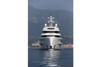 Front view of 2022 Amels Custom yacht on calm water, mountainous backdrop.