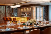 Luxurious dining area on 2022 Amels Custom yacht with elegant decor and bar.