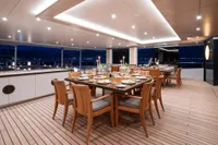 Luxurious dining area on 2022 Amels Custom yacht, featuring elegant wooden furniture and ambient lighting.