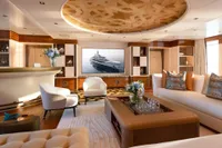 Luxurious 2022 Amels Custom yacht interior with elegant seating, bar, and large TV screen.