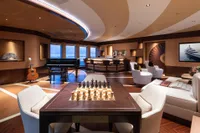 Luxurious 2022 Amels Custom yacht interior with chess set, grand piano, and elegant bar area.