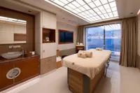 Luxurious yacht spa room with massage table, ocean view, and elegant decor, Amels Custom 2022.
