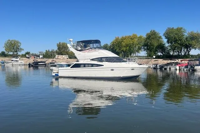  Yacht Photos Pics 2005 Carver 38 Super Sport yacht on calm water, surrounded by trees and other boats.