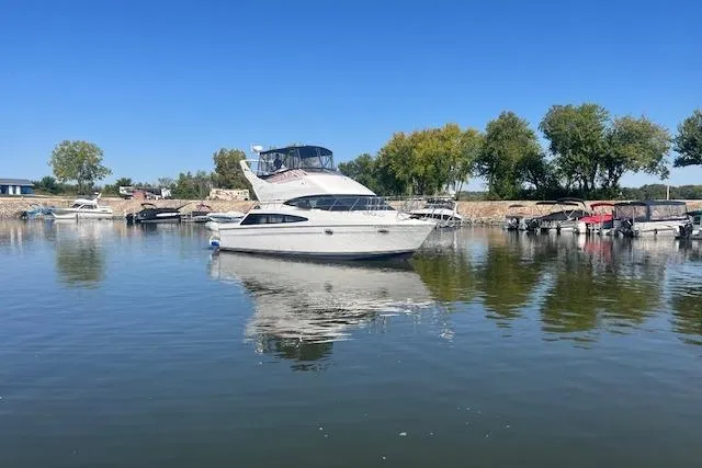  Yacht Photos Pics 2005 Carver 38 Super Sport yacht on calm water, surrounded by trees and boats.