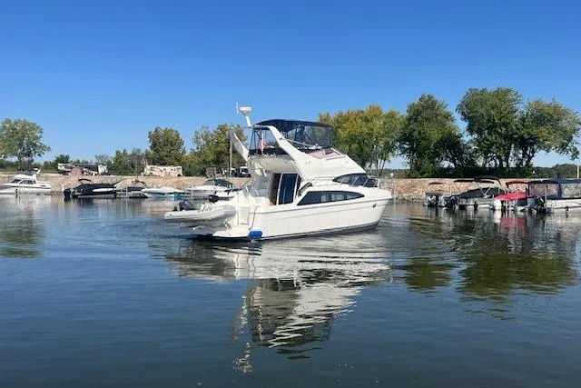  Yacht Photos Pics 2005 Carver 38 Super Sport yacht on calm water, surrounded by trees and docks.