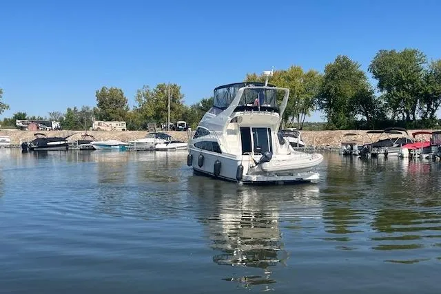  Yacht Photos Pics 2005 Carver 38 Super Sport yacht on calm water near a marina with trees.