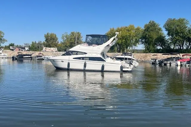  Yacht Photos Pics 2005 Carver 38 Super Sport yacht docked on calm water, surrounded by trees and boats.