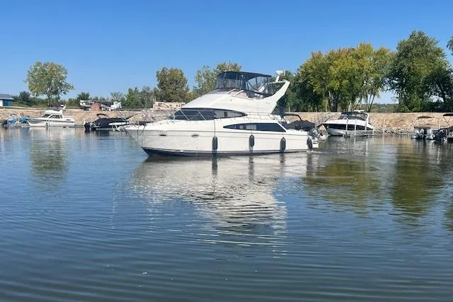 Yacht Photos Pics 2005 Carver 38 Super Sport yacht on calm water, surrounded by trees and other boats.