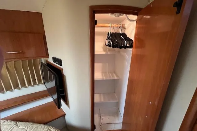  Yacht Photos Pics 2005 Carver 38 Super Sport interior with open closet, hangers, and wooden cabinetry.