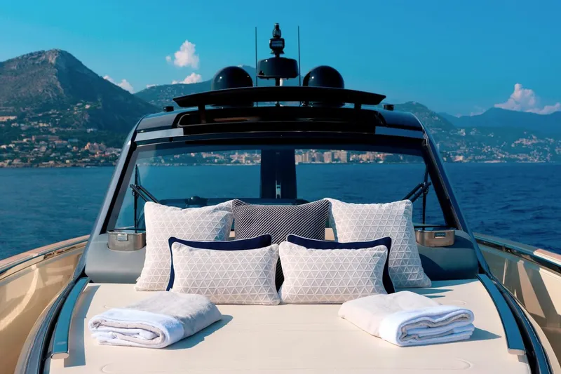  Yacht Photos Pics Luxurious 2023 Invictus TT460 yacht with plush cushions and towels, set against a scenic ocean backdrop.