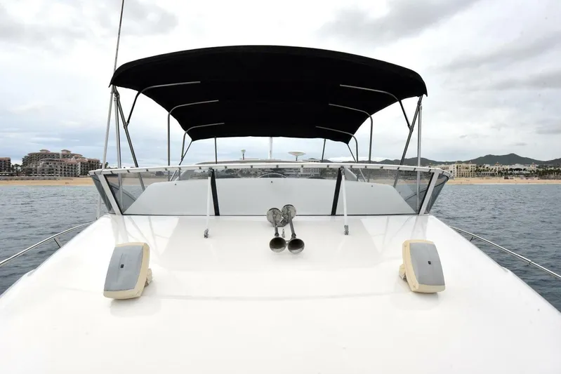 Pura Vida Yacht Photos Pics 2010 Silverton 38 Sedan Bridge yacht with canopy, anchored near a coastal cityscape.