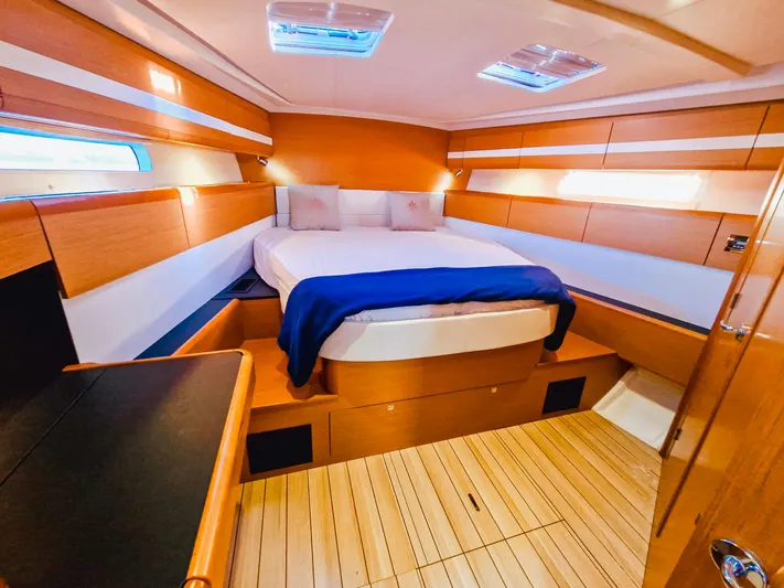  Yacht Photos Pics Luxurious cabin interior of a 2015 Jeanneau 53 yacht with wooden finishes and cozy bedding.