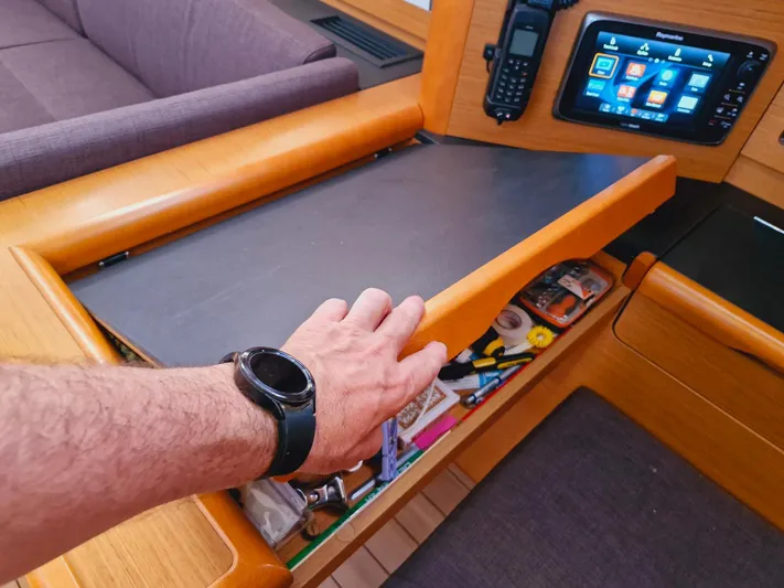  Yacht Photos Pics Hand opening a drawer on a 2015 Jeanneau 53 yacht, revealing navigation tools.
