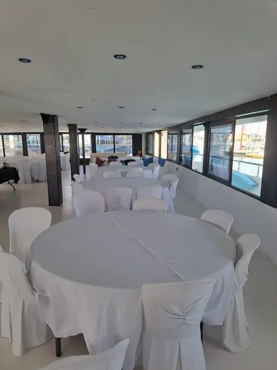 Salone Yacht Photos Pics Interior of a 2015 Power Catamaran with round tables and white chairs.