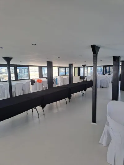 Salone Yacht Photos Pics Interior of a 2015 Power Catamaran set up for an event with tables and chairs.