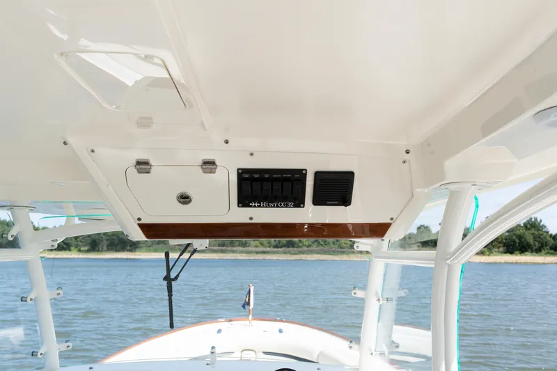 Hunt 32cc-035 Yacht Photos Pics 2019 Hunt Yachts 32CC helm with control panel, overlooking serene water and shoreline.