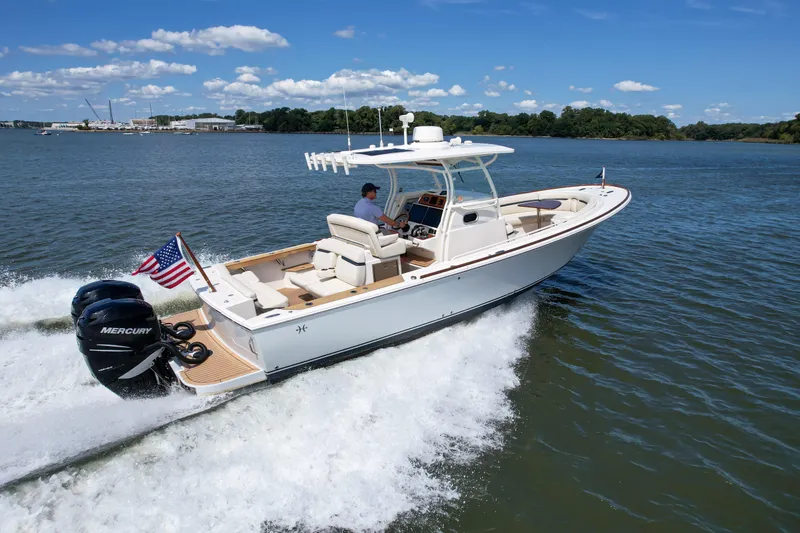Hunt 32cc-035 Yacht Photos Pics 2019 Hunt Yachts 32CC cruising on water with American flag, clear sky, and lush shoreline.