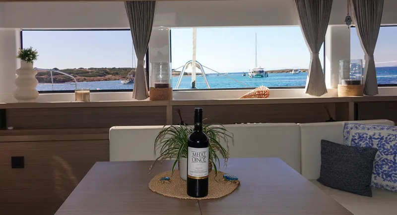 Esperance Yacht Photos Pics Interior of 2024 Lagoon 55 yacht with sea view and wine bottle on table.