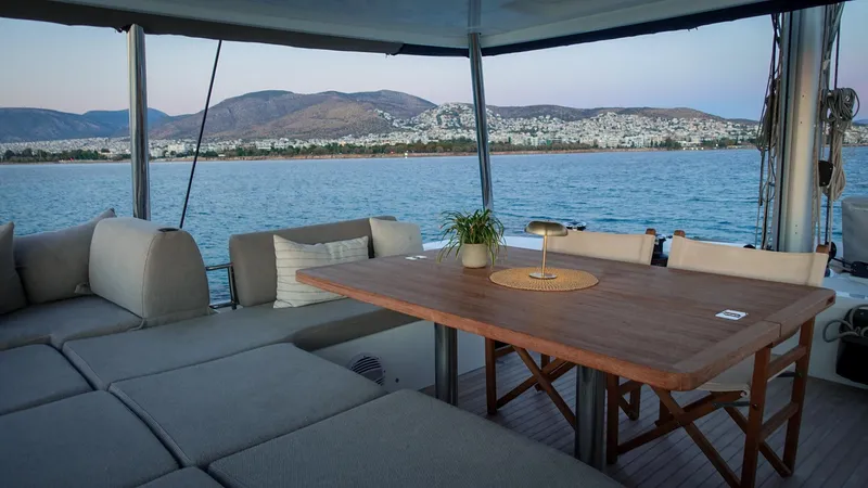 Esperance Yacht Photos Pics Luxurious 2024 Lagoon 55 yacht deck with seating, table, and scenic coastal view.