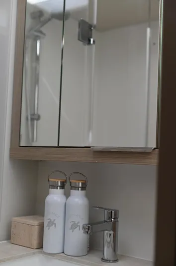 Esperance Yacht Photos Pics Modern bathroom vanity with mirror, faucet, and two water bottles on a Lagoon 55 yacht.