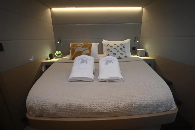 Esperance Yacht Photos Pics Luxurious bedroom interior of 2024 Lagoon 55 yacht with cozy bedding and ambient lighting.