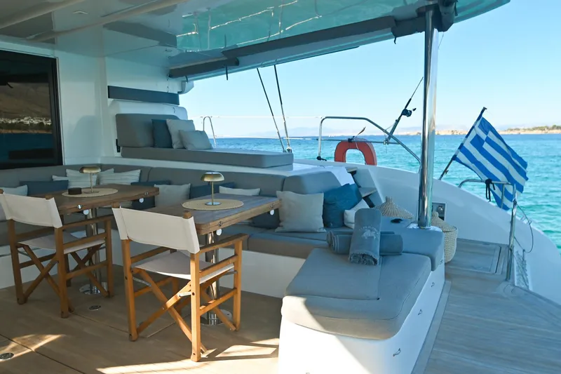 Esperance Yacht Photos Pics Luxurious Lagoon 55 yacht deck with seating, tables, and Greek flag, 2024 model.
