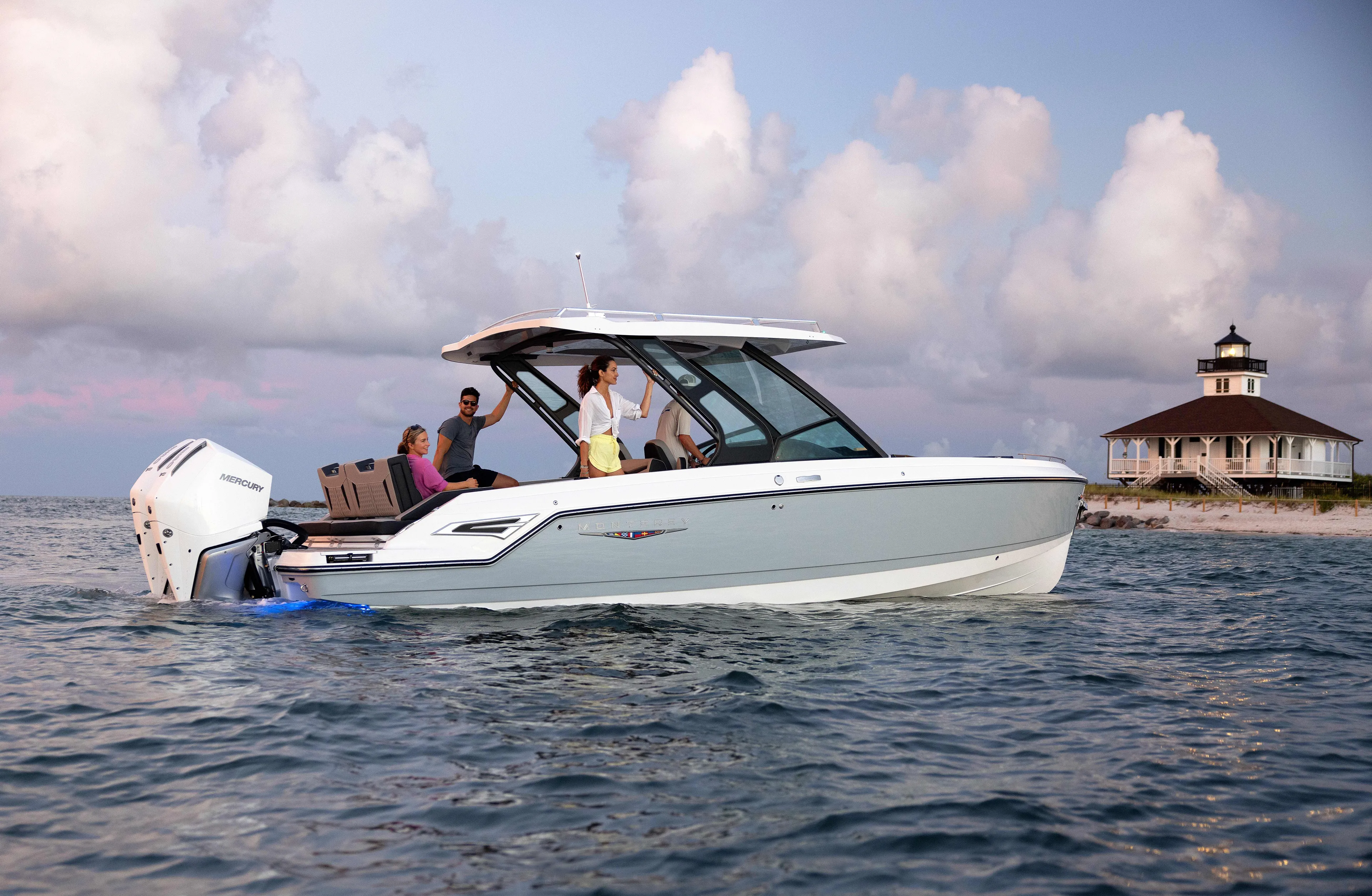  Yacht Photos Pics 2026 Monterey ELITE 30 boat cruising near a lighthouse under a cloudy sky.