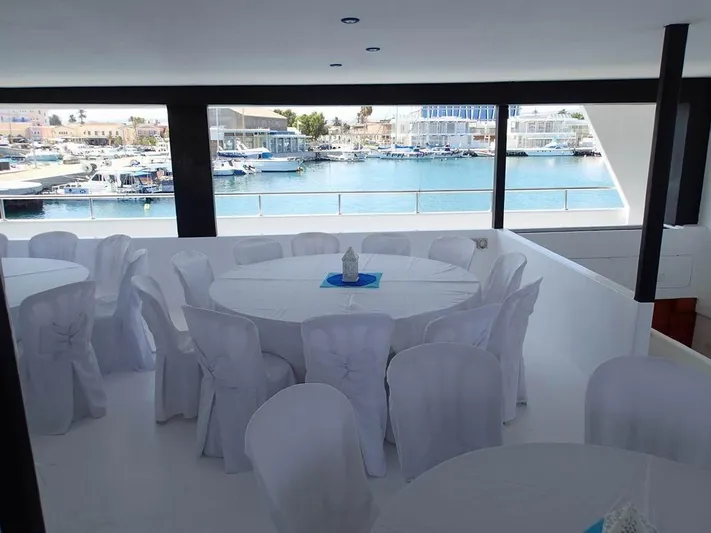 Salone Yacht Photos Pics Interior of a 2015 Power Catamaran with elegant white-covered tables and chairs.
