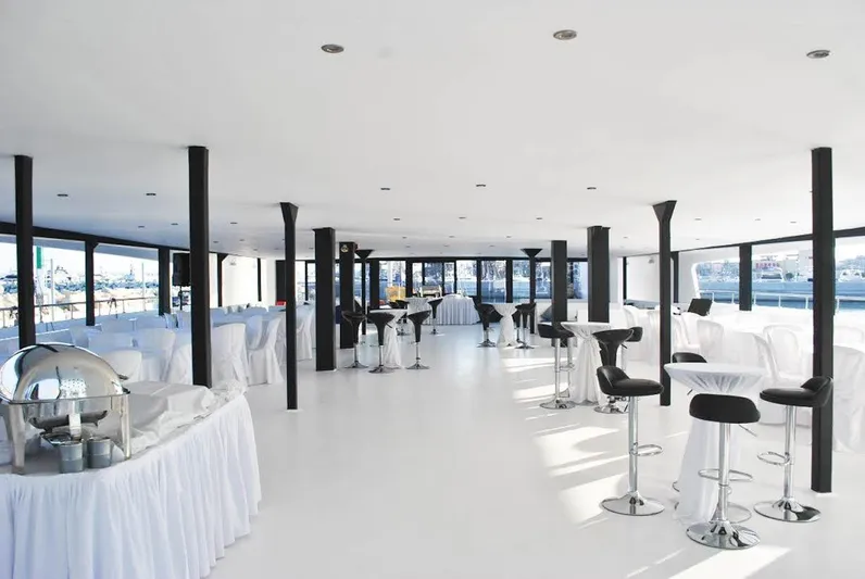 Salone Yacht Photos Pics Spacious interior of a 2015 Power Catamaran set up for an event with tables and chairs.