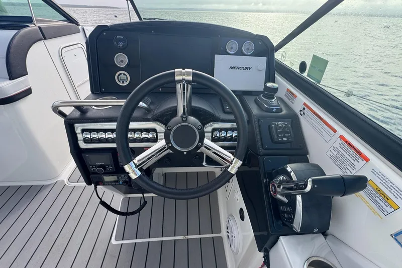  Yacht Photos Pics 2022 Formula 310 Bowrider OB helm with steering wheel and control panel, overlooking water.