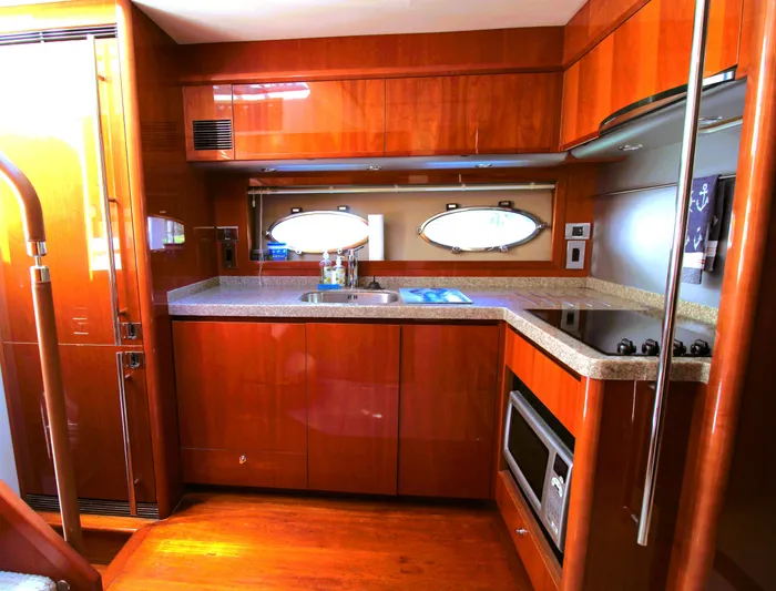 Ahdorned Yacht Photos Pics Luxurious yacht kitchen interior with wood cabinetry, modern appliances, and oval porthole window. Princess F54, 2009.