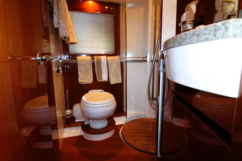 Ahdorned Yacht Photos Pics Luxurious yacht bathroom with wooden accents, featuring a toilet, shower, and elegant fixtures.
