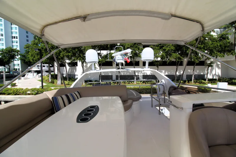 Ahdorned Yacht Photos Pics Luxurious 2009 Princess F54 yacht deck with seating and table, docked near greenery.