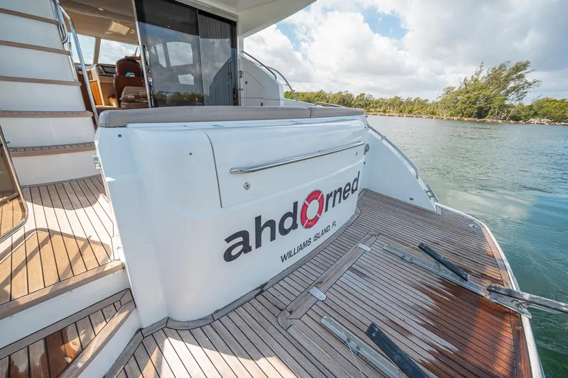 Ahdorned Yacht Photos Pics Luxury Princess F54 yacht deck with wooden flooring, docked near lush shoreline.