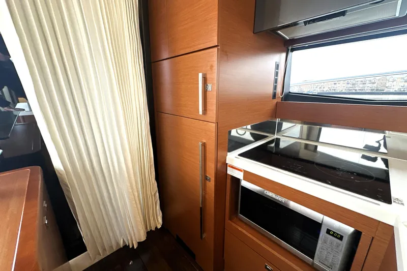 Cyctrade Yacht Photos Pics Modern kitchen interior on a 2017 Prestige 500 yacht, featuring wood cabinetry and appliances.