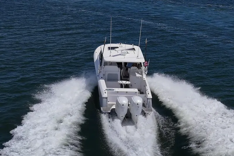  Yacht Photos Pics 2022 Southport 33 DC boat cruising on open water, rear view.