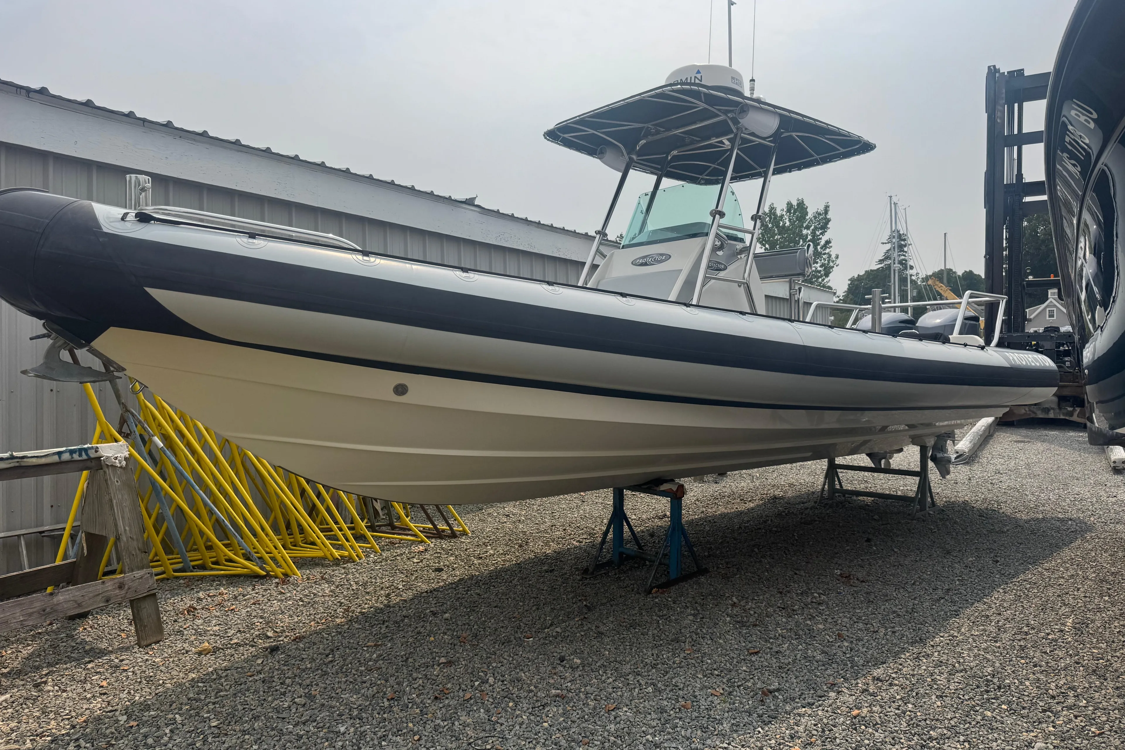 2016 Protector 30 Center Console boat on stands in a gravel yard.