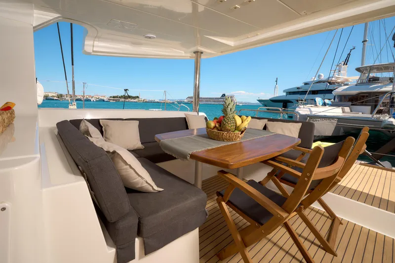  Yacht Photos Pics Luxurious 2019 Lagoon 52 F yacht deck with dining area, fruit basket, and ocean view.