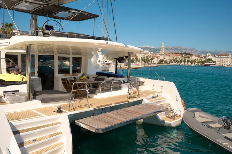  Yacht Photos Pics 2019 Lagoon 52 F yacht docked in a scenic harbor with cityscape background.