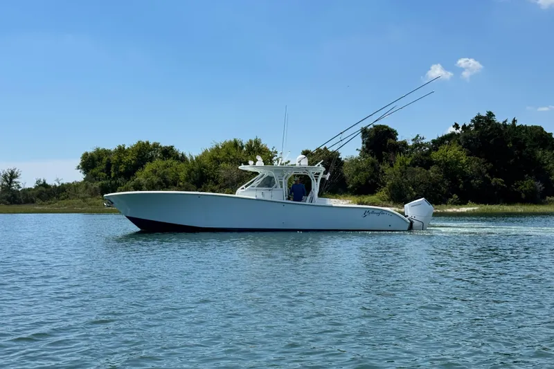  Yacht Photos Pics 2014 Yellowfin 42 Offshore boat cruising on a sunny day near lush shoreline.
