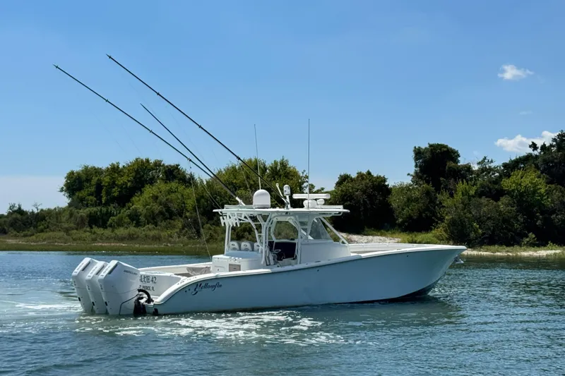  Yacht Photos Pics 2014 Yellowfin 42 Offshore boat cruising on a sunny day near a lush shoreline.
