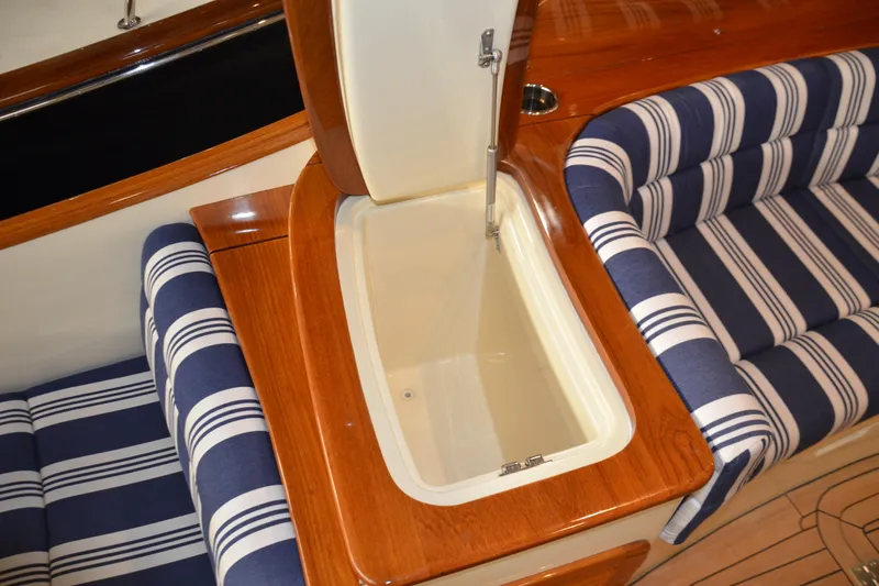 Standish Yacht Photos Pics 2017 Hinckley Picnic Boat 37 MKIII interior with striped seating and wooden storage compartment.