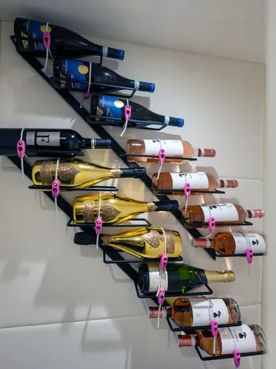  Yacht Photos Pics Wall-mounted wine rack on Pershing 82 yacht, displaying assorted wine bottles.