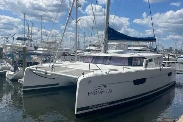 Endeavour Yacht Photos Pics 2020 Fountaine Pajot Saona 47 catamaran docked in a marina under a cloudy sky.