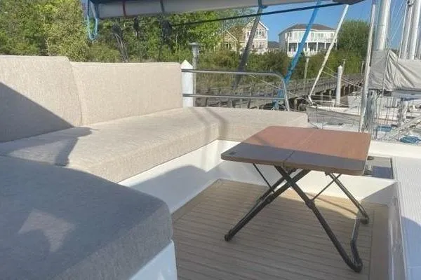 Endeavour Yacht Photos Pics Outdoor seating area on a 2020 Fountaine Pajot Saona 47 catamaran with a wooden table.